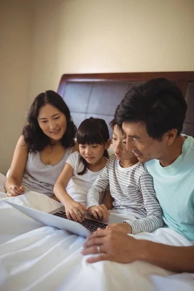 Familj med laptop tillsammans i sovrum — Stockfoto