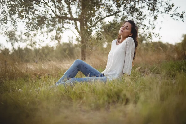 Çiftliğinde çimenli alan üzerinde oturan kadın — Stok fotoğraf