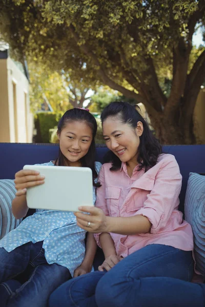 Anne ve kızı tablet kullanarak kanepede rahatlatıcı — Stok fotoğraf