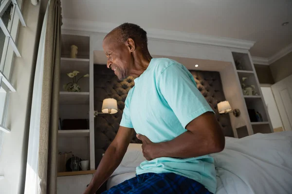 Старший мужчина страдает от болей в животе дома — стоковое фото