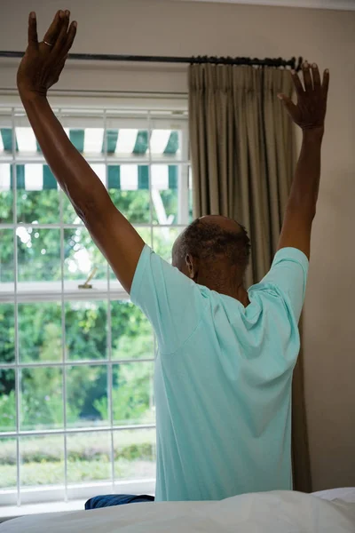 Man stretching arms while sitting on bed — Stock Photo, Image