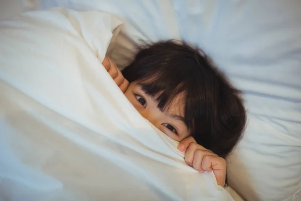 Niño escondido en la cama debajo de la manta — Foto de Stock