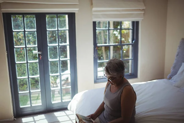 Seniorin liest Buch im Bett — Stockfoto