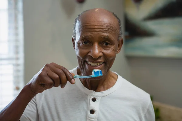 senior man brushing teeth in bathroom