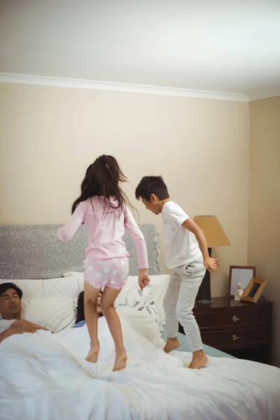 Hermanos saltando en la cama en el dormitorio — Foto de Stock