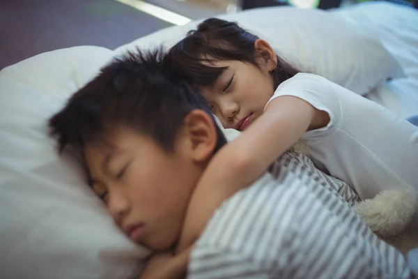 Братья и сёстры спят на кровати в спальне — стоковое фото