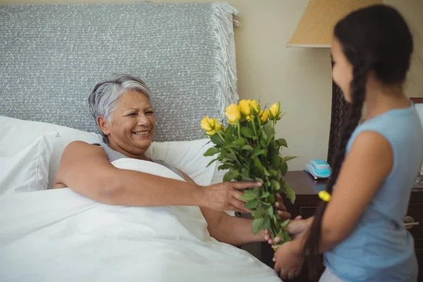 Kleindochter bloemen geven grootmoeder — Stockfoto