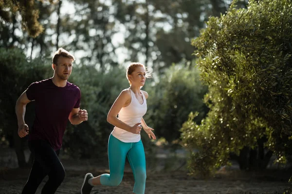 Determined young couple running on field — Stock Photo, Image