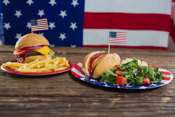 Hamburger a párek v rohlíku na stůl s motivem 4. července — Stock fotografie