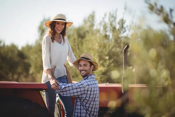 Muž hospodářství přítelkyně stojící na traktoru — Stock fotografie