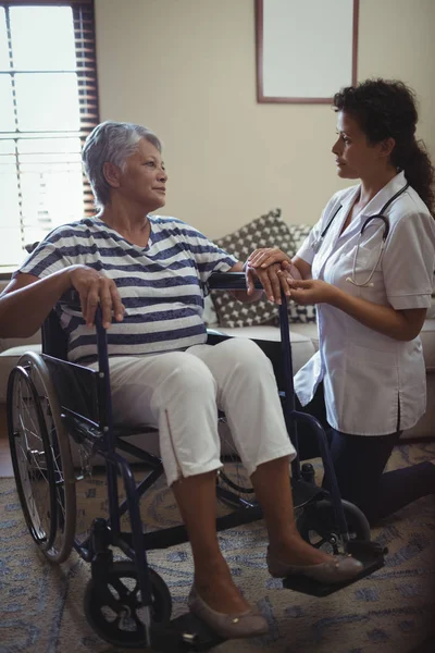 Doctor interactuando con la mujer en silla de ruedas — Foto de Stock