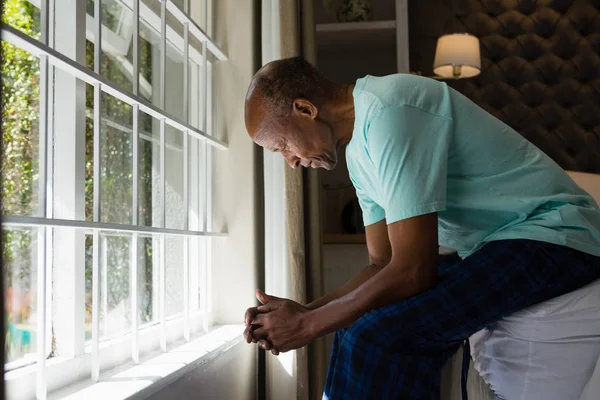 Senior man sitting by window in bedroom — Stock Photo, Image