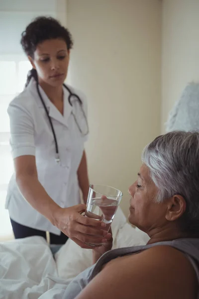 Medico che dà alla donna malata un bicchiere d'acqua — Foto Stock