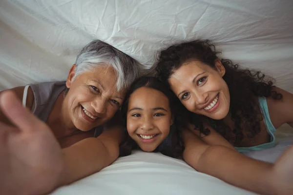Семья, лежащая на кровати в спальне — стоковое фото