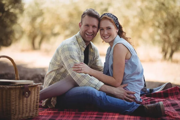 Пара, сидящая на коврике на оливковой ферме — стоковое фото
