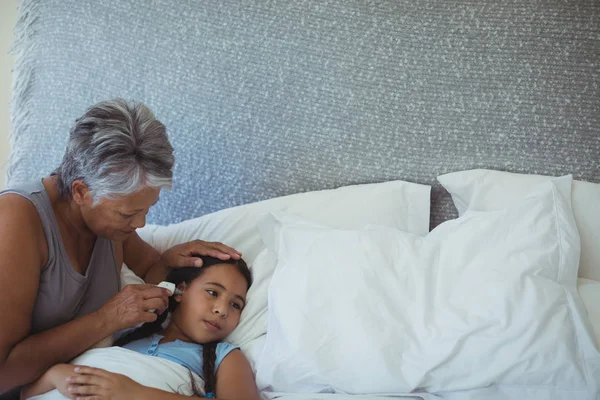 La abuela comprobando la temperatura corporal de la nieta enferma — Foto de Stock