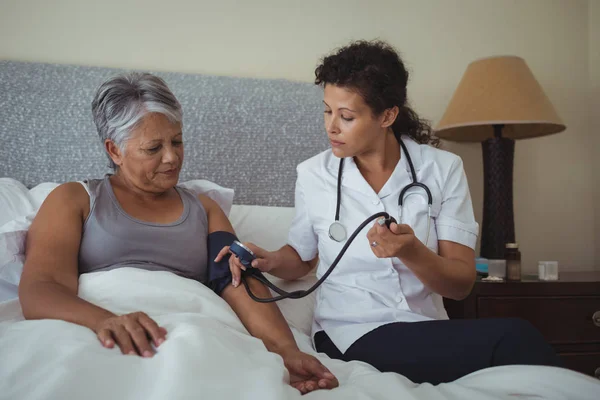 Doctor measuring blood pressure of woman — Stock Photo, Image