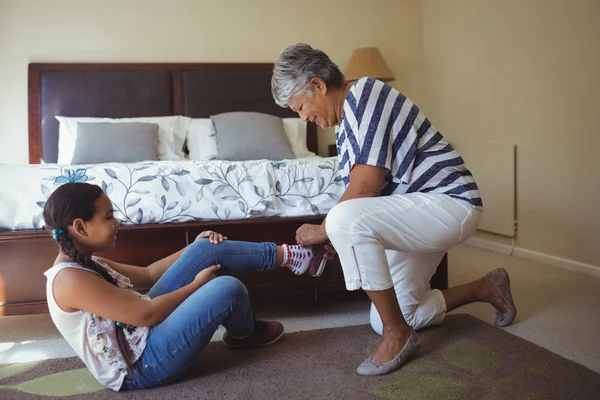 Großmutter hilft Enkelin, Schuhe zu tragen — Stockfoto