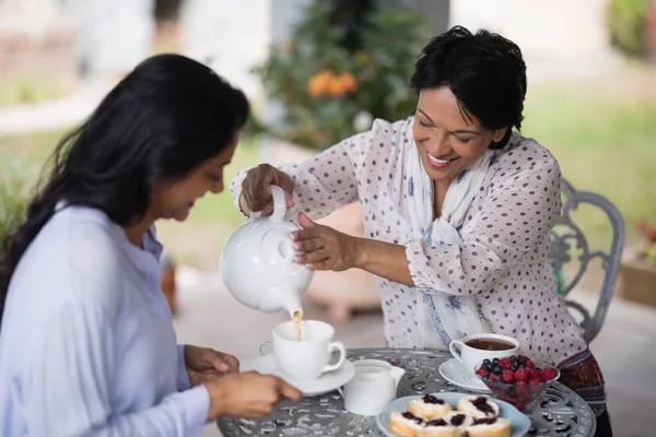 Mujer verter té en taza para hija — Foto de Stock