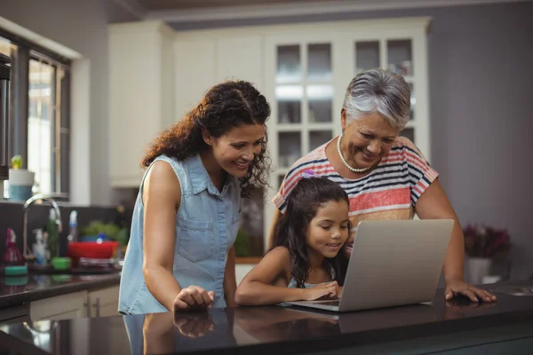 Happy family using laptop in kitchen — Stock Photo, Image