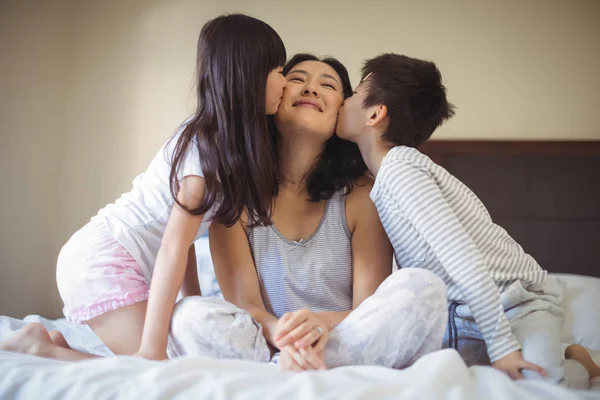 Beijando a mãe nas bochechas no quarto de cama — Fotografia de Stock