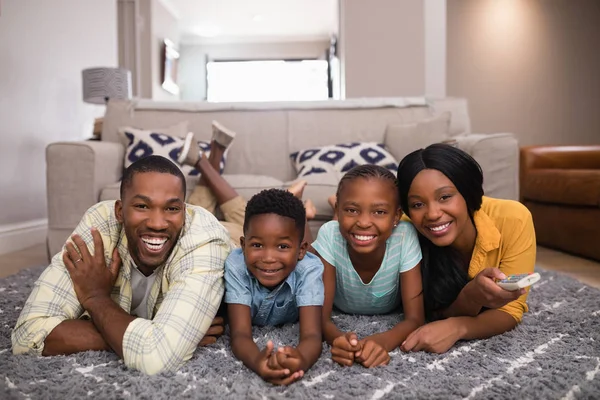 Família assistindo televisão enquanto deitado no tapete — Fotografia de Stock