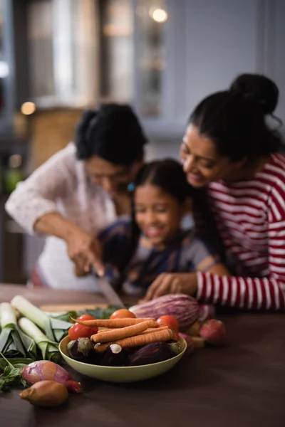 Zelenina na stole proti vícegeneračním rodinné — Stock fotografie