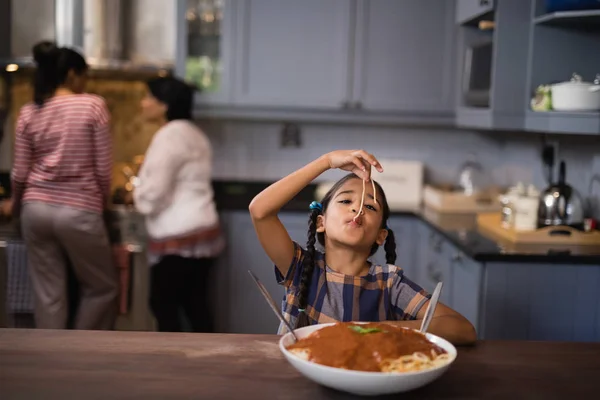 Девушка ест спагетти на кухне — стоковое фото