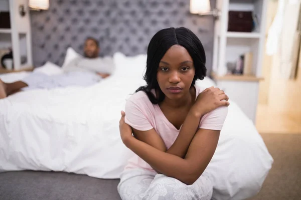 Woman sitting while man lying on bed — Stock Photo, Image