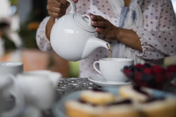 Prostřední část ženy nalévání čaje v šálku — Stock fotografie