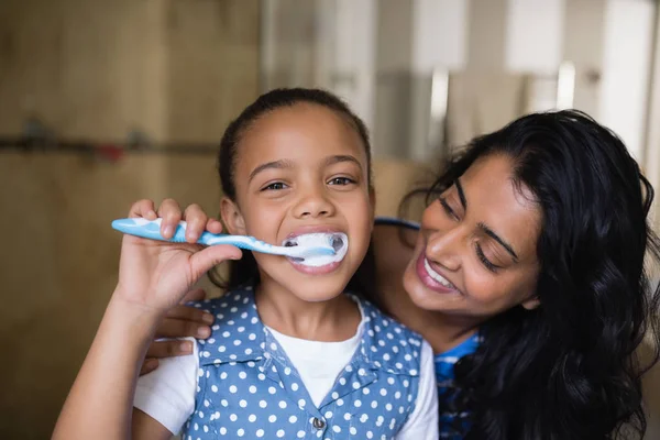 Girl brushing teeth with mother — Stock Photo, Image