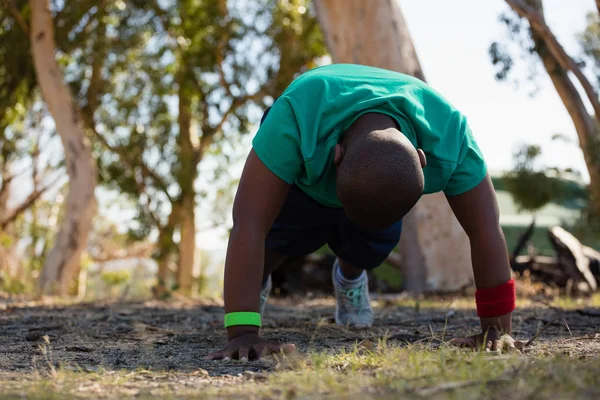 Niño haciendo ejercicio durante el entrenamiento de carrera de obstáculos —  Fotos de Stock