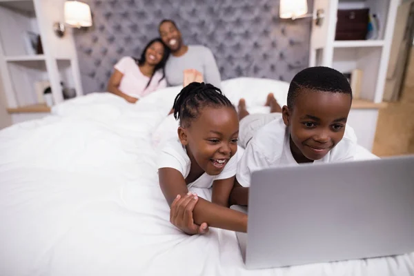 Irmãos usando laptop na cama — Fotografia de Stock