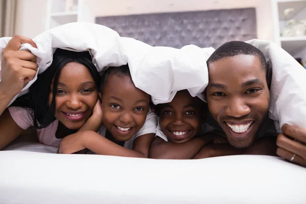 Birlikte yatakta battaniyenin altında yalan aile — Stok fotoğraf