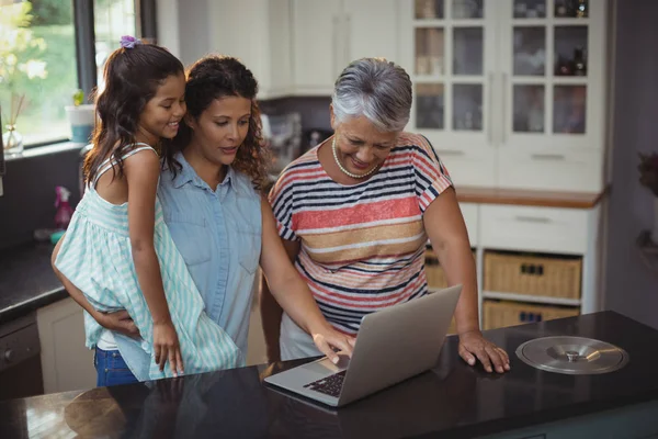 Family using laptop in kitchen — Stock Photo, Image