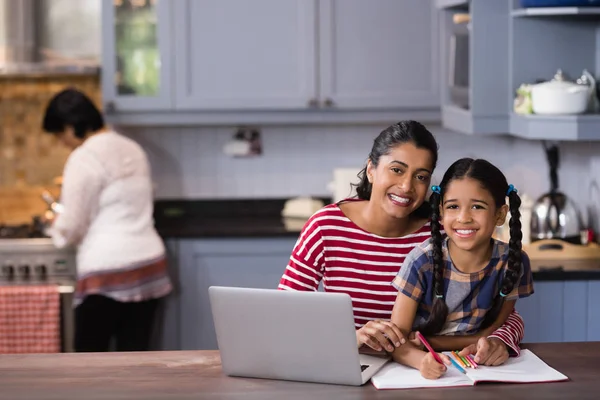 Girl with mother studying in kitchen — Stock Photo, Image