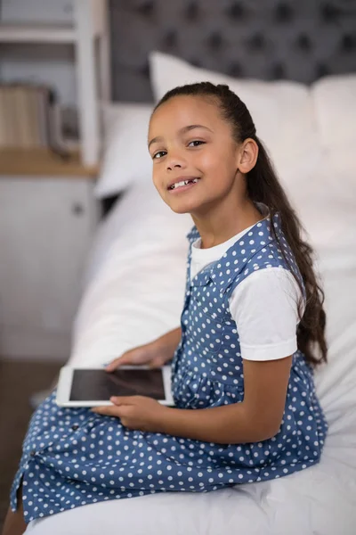 Dívka drží tablet sedí na posteli — Stock fotografie