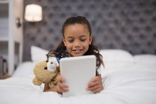 Fille à l'aide de la tablette tout couché sur le lit — Photo