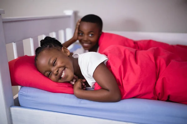 Broers en zussen liggend op bed thuis — Stockfoto