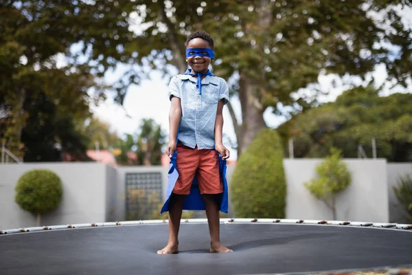 Garçon en costume de super-héros sur trampoline — Photo