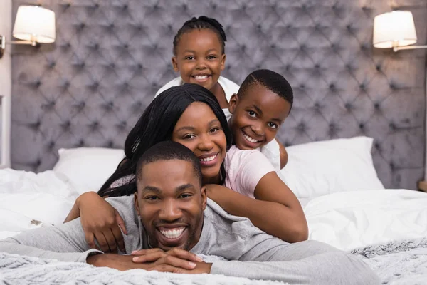 Famiglia sorridente sdraiata sul letto — Foto Stock