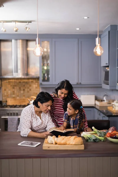 Libro de lectura familiar multigeneración en la cocina —  Fotos de Stock