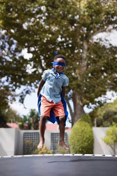 Chlapec v kostýmu superhrdiny, skákání na trampolíně — Stock fotografie