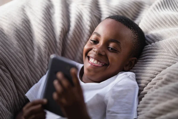 Pojke som leker med telefonen på soffan — Stockfoto