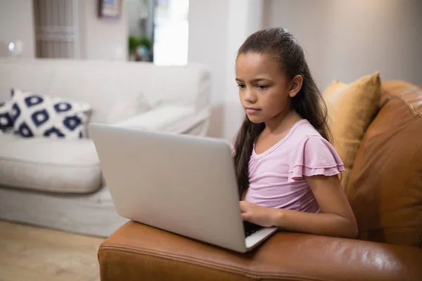 Flicka använder laptop medan du sitter på soffan — Stockfoto