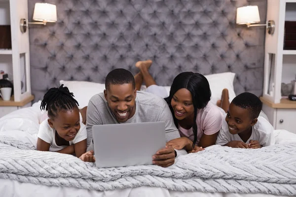 Familj med laptop liggande tillsammans på sängen — Stockfoto