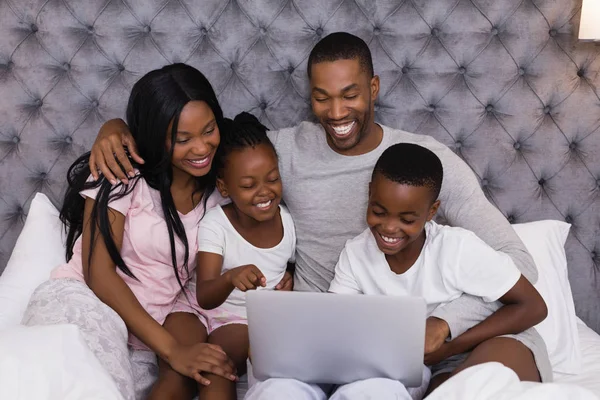 Семья использует ноутбук вместе на кровати — стоковое фото