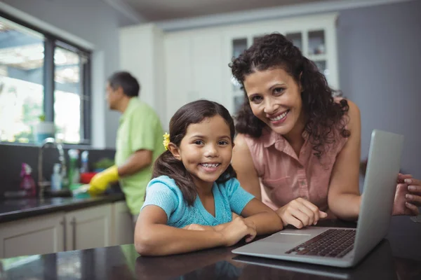 Madre e figlia utilizzando il computer portatile in cucina — Foto Stock