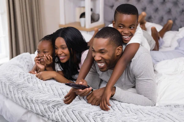 Família assistindo televisão enquanto deitado na cama — Fotografia de Stock