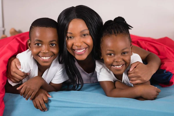 Femme avec des enfants couchés sur le lit — Photo